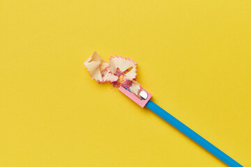 Sharpener with sticking out blue pencil and pink shavings.
