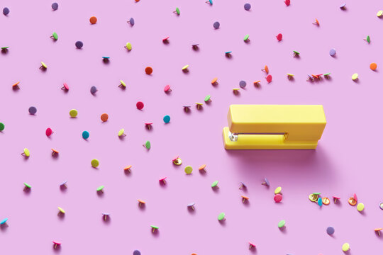 Yellow stapler breaking pattern of multicolored pins.