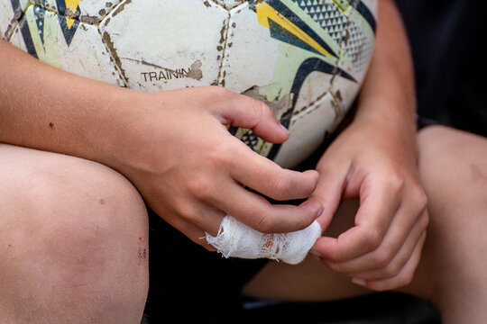 hand with bandaged finger holding soccer ball