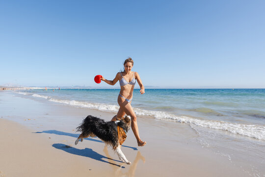 woman running on the beach with her dog