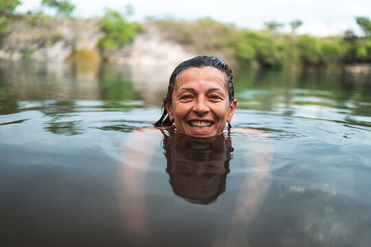 smiling wet woman swimming in a lake