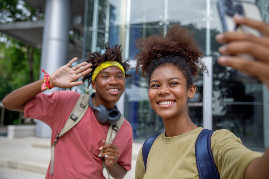 Girl taking selfie with friend waving hand saying hello