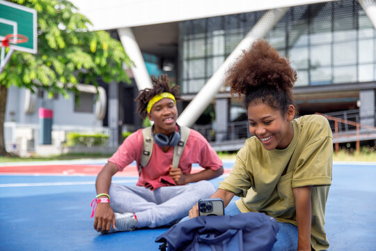 Friends using mobile phone on outdoor sports court