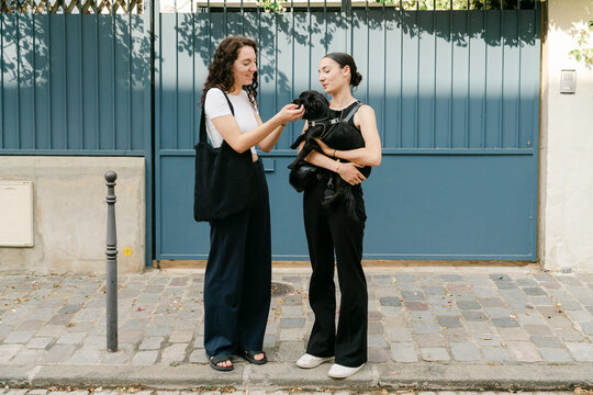 two young women petting their little dog in Pris France. 