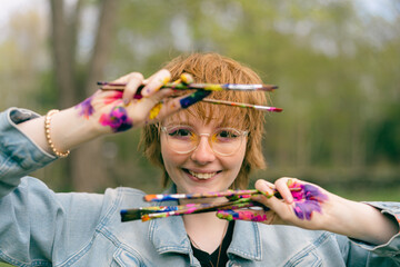fun portrait of happy artist holding paint brushes