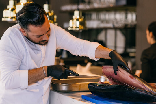 Professional chef preparing fish in kitchen