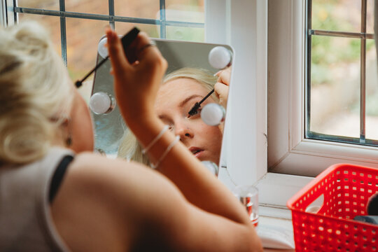 Teenage Girl Looking In A Mirror And Applying Mascara