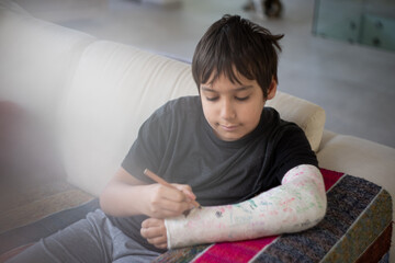 Kid with broken arm writing his name on his cast