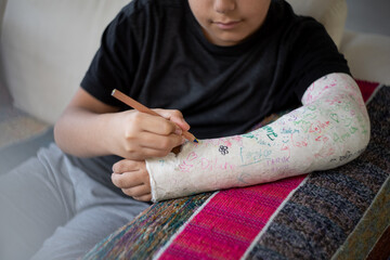 Kid with broken arm writing his name on his cast
