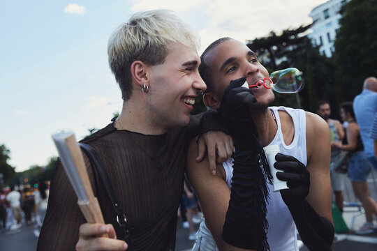 Queer friends hugging and playing with bubbles during pride
