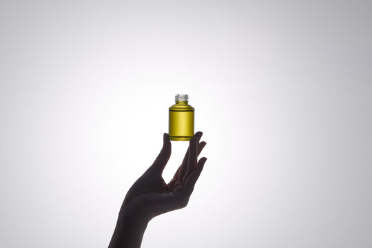Woman hand holding facial essential oil or serum packaging.