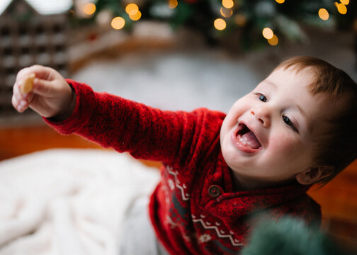 Happy baby decorates a Christmas tree with string lights