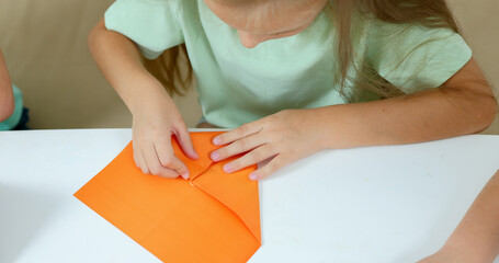 Girl fold origami according to a video lesson, online training