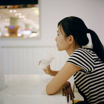 The woman with a ponytail is drinking milk tea
