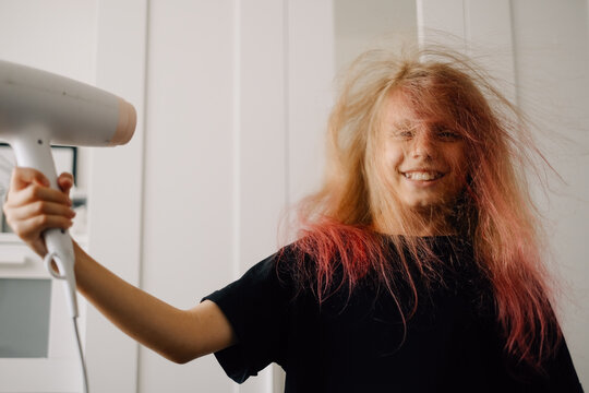 Teenage girl drying her hair after dyeing it pink