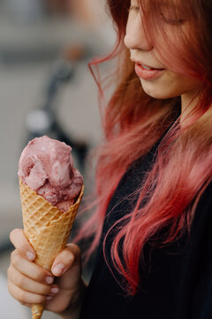 Teenage girl with pink hair holding ice cream