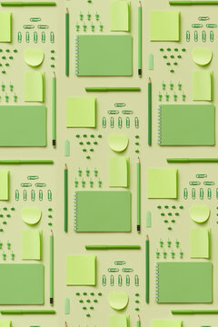 Pattern with various green-colored office supplies.
