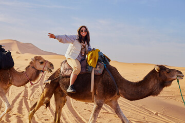 Joyful tourist explores the desert on a guided camel tour.