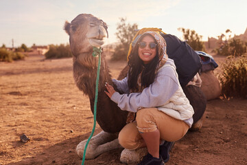 A joyful explorer poses with the camel after a guided tour.