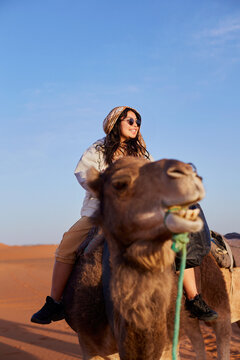 A happy woman discovering the desert while riding a camel.