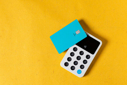A blue credit card on a white wireless terminal payment