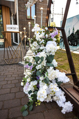 Stylish wedding arch for the newlyweds, decorated with fresh flowers in the city against the backdrop of the building during the day. Image about wedding decor and ceremony.
