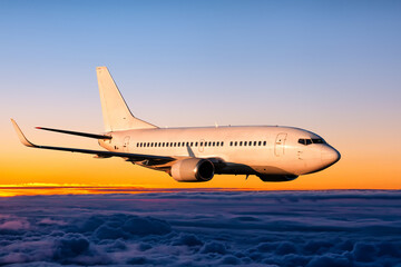 Fototapeta na wymiar White passenger airplane is flying in the sunrise sky