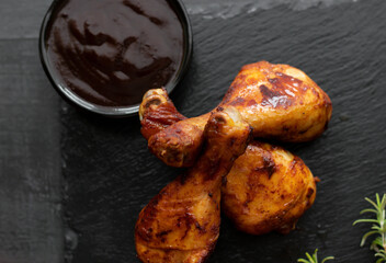 Grilled chicken wings with rosemary and spices and barbecue sauce. on a black background