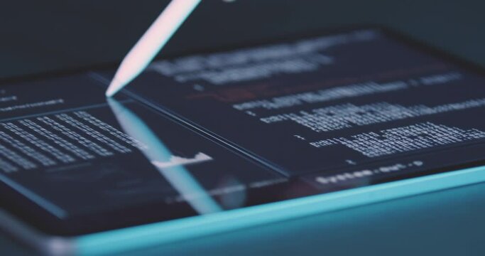 Programmer looks at lines of code of program on tablet screen and moves with an input pen stylus