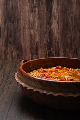 Authentic mexican chicken tinga, typical mexican food prepared in a clay pot on a wooden table.