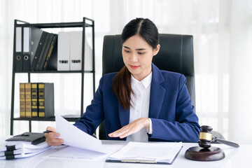 Attractive young lawyer in office Business woman and lawyers working contract papers with brass scale on wooden desk in office. Law, legal services, advice, Justice and real estate concept.