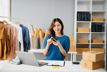 Asian lady blogger showing clothes in front of the camera to recording vlog video live streaming at her shop. Online Shopping