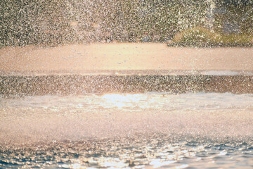 The background of water splashes waterfall from a fountain, the texture of drops in the sun