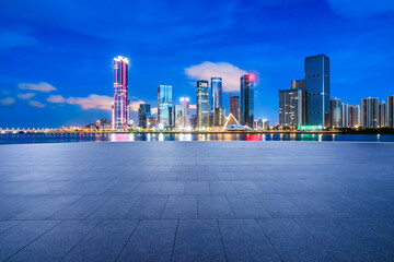Empty square floor and city skyline with modern buildings scenery at night