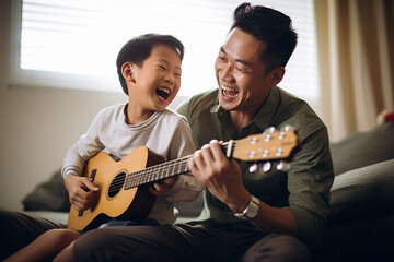 Asian father teaching his son to play guitar or ukulele. They are laughing, singing
