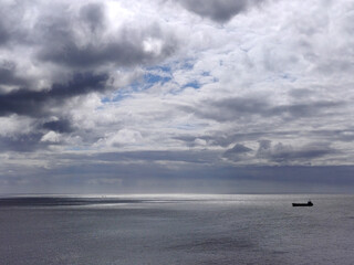 Obraz premium Cargo ship in the open stormy sea. With heavy rainy sky background