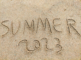 Verano 2023 escrito en la arena de la playa.
