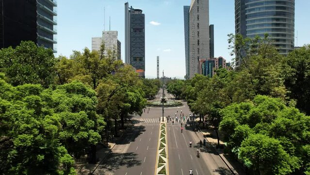 backwards drone shot of cyclists exercising on reforma avenue in mexico city