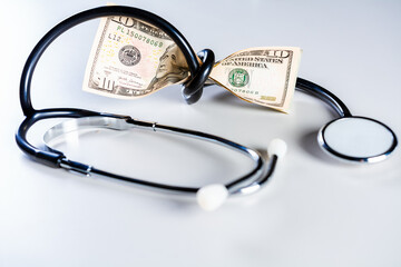 High cost of medical health with stethoscope. Stethoscope wrapped around money isolated, Stethoscope tied with dollar bills