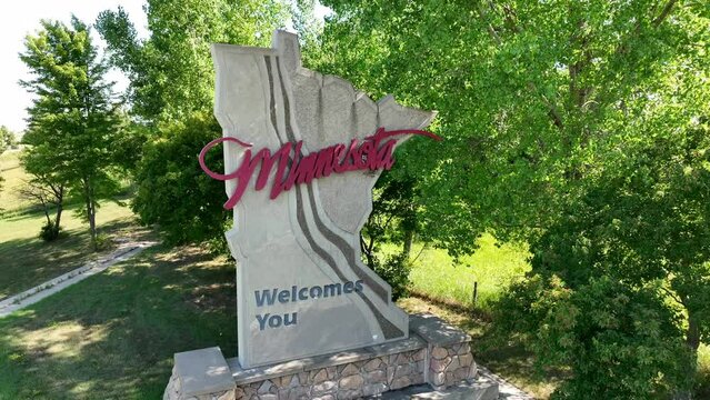 Minnesota Welcomes you sign. Aerial orbit around landmark at state border in the shape of MN state. Summer shot.