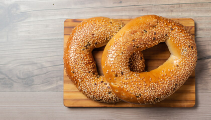 Two sesame bagels on wooden cutting board. Table top view