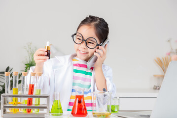 Asian little girl working with test tube science experiment in white classroom