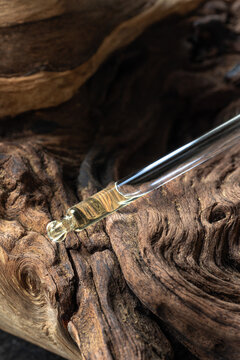 Glass dropper with essential oil or serum on beautiful textured wooden background 
