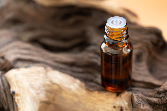 Dark glass cosmetic bottle with essential oil or serum on wooden texture background