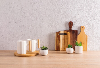 A set of cutting wooden boards and two trendy white ceramic mugs on a wooden kitchen countertop. Modern kitchen interior. eco-items.