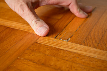 Old damaged parquet with loose strips (strip parquet) is examined by a specialist before it is reconditioned by re-sanding.