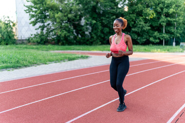 Obraz premium The confident black woman casually jogs on a running track, exuding grace and ease. Her relaxed stride inspires with its effortless beauty, showcasing her love for running