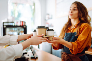 Beautiful barista woman issues coffee orders to go in a coffee shop. Small business owner. Takeaway food and drinks.