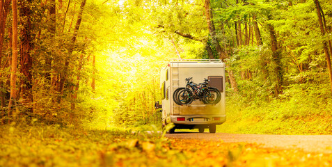 motorhome on road in forest at sunrise- travel, adventure,vacation concept