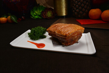 famous crispy roasted bbq pork belly meat cut slices in long plate on black background Hong Kong banquet food appetiser menu for restaurant